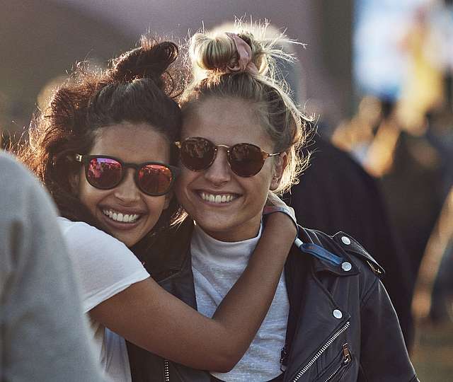 zwei junge Frauen mit Sonnenbrille, die sich umarmen