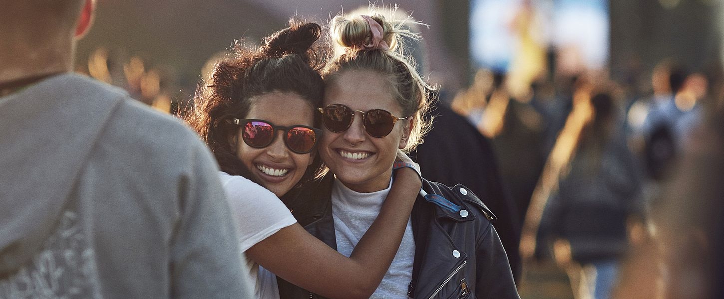zwei junge Frauen mit Sonnenbrille, die sich umarmen