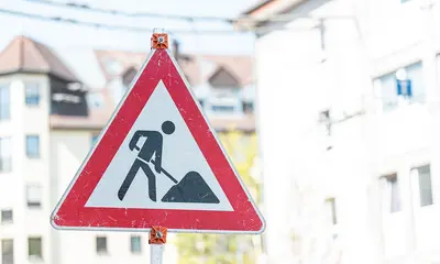 Dreieckiges Straßenverkehrsschild, das mit einem stilisierten Bauarbeiter auf eine Baumaßnahme hinweist