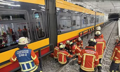 Mehrere Feuerwehrleute stehen neben einer Bahn. Sie versuchen während eine Übung die Bahn mit technischem Werkzeug zu heben.