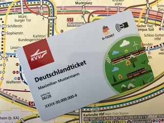 Ein Deustchlandticket im Scheckkartenformat vor einem ÖPNV-Liniennetzplan