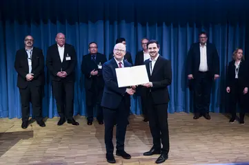 Das Foto zeigt Staatssekretär Michael Theurer bei der Übergabe einer Urkunde an VBK-Projektleiter Ruben Jerke. 