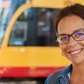 Eine junge Frau sitzt im Bus und schaut lachend über ihre Schulter nach hinten.