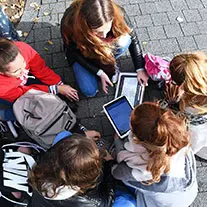 Kinder stehen im Kreis und haben ein Tablet in der Hand