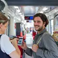 Mann zeigt einer Kontrolleurin seine Fahrkarte auf dem Smartphone.