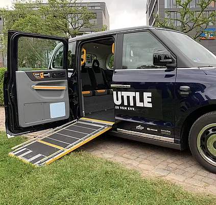 Bild des London-Taxis, das als KVV.MyShuttle barrierefrei unterwegs ist. Eine Rampe ermöglicht die Beförderung von Rollstühlen und Rollatoren.