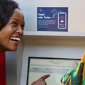 Kleines Mädchen zieht ein Ticket am Fahrkartenautomat und lacht dabei in die Kamera.