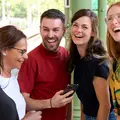Drei Jugendliche halten eine Einkaufstüte. Zwei schauen in die Tüte. Die dritte schaut lächelnd geradeaus.