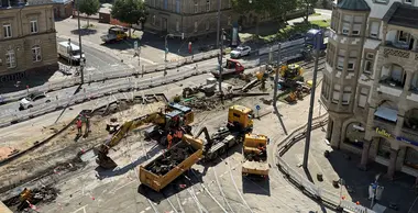 Blick auf die Baustelle an der Tullastraße. Es sind gelbe Bagger und Lastwagen zu sehen. 