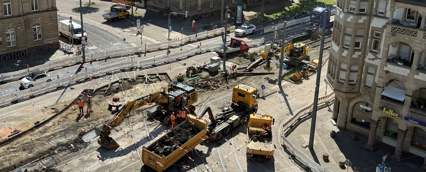 Blick auf die Baustelle an der Tullastraße. Es sind gelbe Bagger und Lastwagen zu sehen.