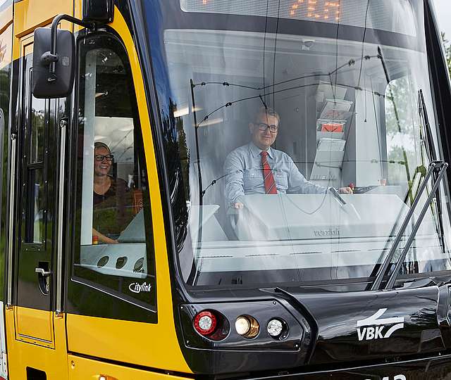Ein Bahnfahrer sitzt lächelnd in der Fahrerkabine.