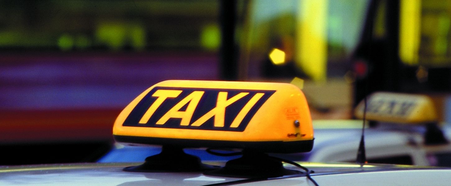 Ein gelbes Taxischild auf dem Dach eines Taxis.