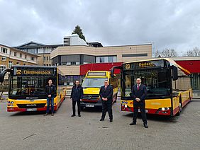 VBK-Mitarbeiter stehen vor drei neuen, gelb-roten Bussen. 
