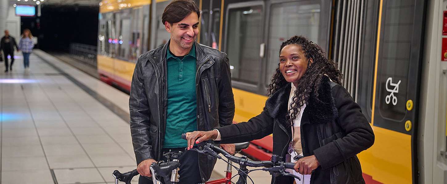 Eine Frau und ein Mann steigen mit ihren Fahrrädern aus einer KVV-Bahn.
