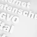 Illustration von Worten in weiß, die aus einem weißen Hintergrund hervortreten. Zu erkennen sind die Worte DSGVO, Datenschutz und digital.