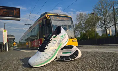 Ein Paar Laufschuhe liegt auf einem Bahnsteig. Im Hintergrund hält eine gelbe Trambahn