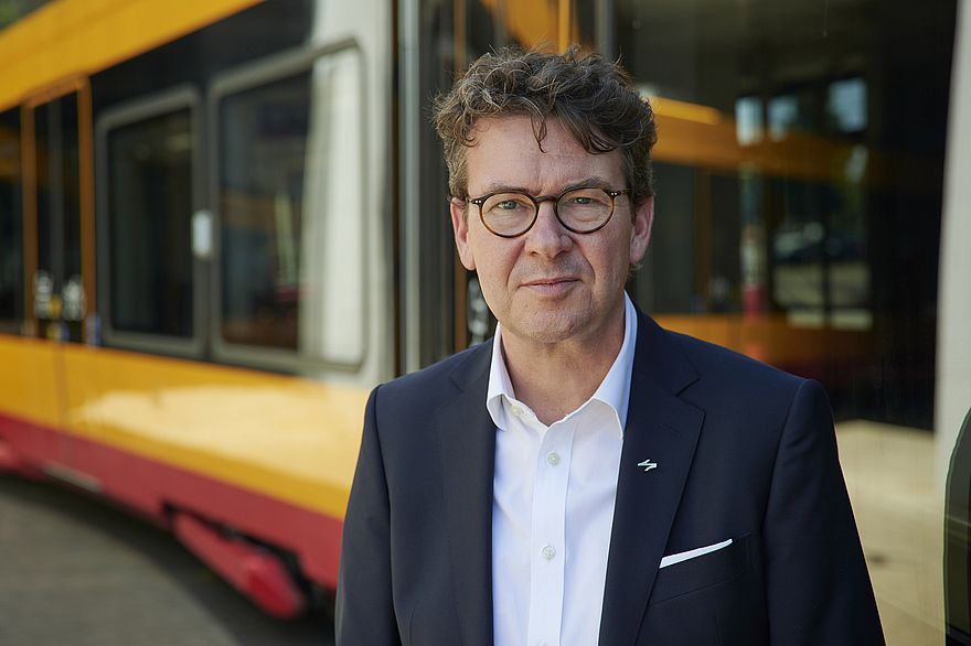 Herr Dr. Pischon, Geschäftsführer des Karlsruher Verkehrsverbund, vor einer Bahn