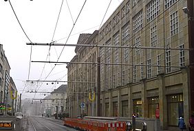 Oberleitungen in der Kaiserstraße. Im Hintergrund befindt sich eine Gebäudefassade.
