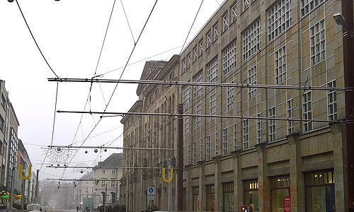 Oberleitungen in der Kaiserstraße. Im Hintergrund befindt sich eine Gebäudefassade.