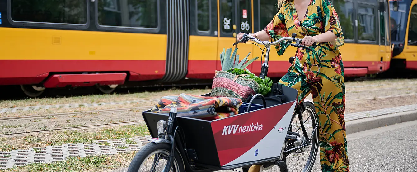 Eine Frau steht neben einem Lastenfahrrad.