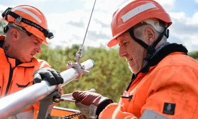 Zwei Techniker der DB Netz AG reparieren eine Oberleitun.