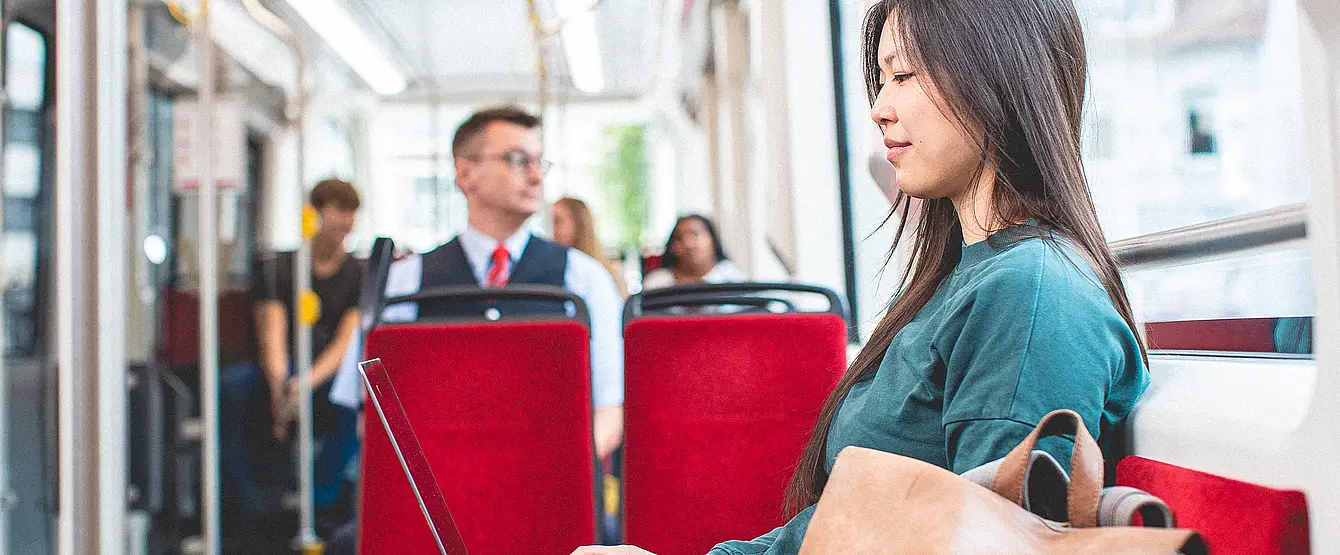 Junge Frau sitzt in der Bahn an ihrem Laptop.