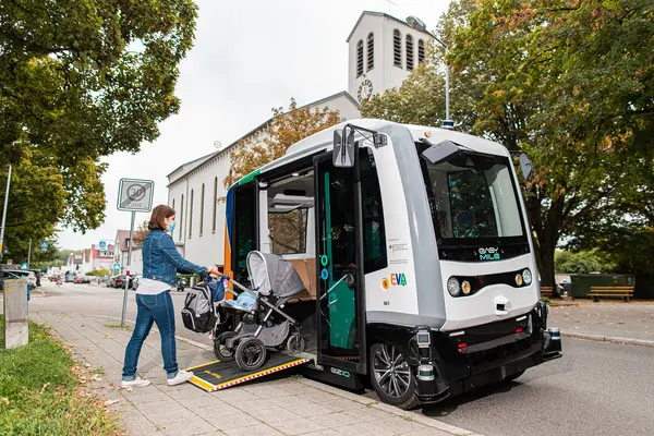 Frau steigt mit Kinderwagen in ein autonomes Shuttle