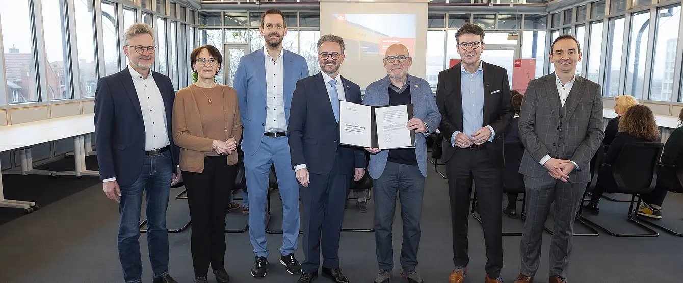 Gesellschafterbeitritt: Die Gesellschafter halten einen unterschriebenen Gesellschaftervertrag in die Kamera und lachen. 