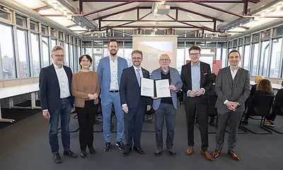 Gesellschafterbeitritt: Die Gesellschafter halten einen unterschriebenen Gesellschaftervertrag in die Kamera und lachen. 