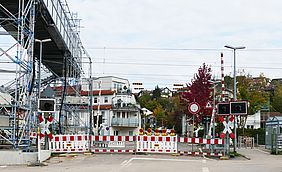 Rot-weiße Absperrbarken am Bahnübergang Söllingen und links davon steht die Behelfsbrücke für Fußgänger.